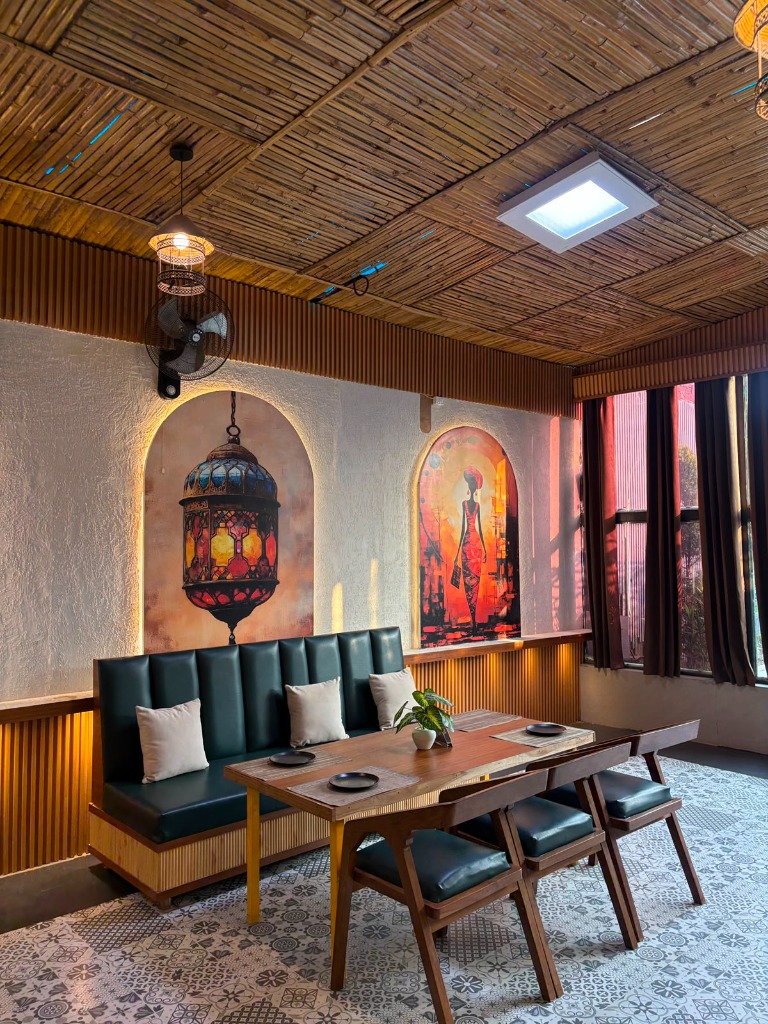 Get 2 Gather authentic interior featuring handcrafted bamboo ceiling, illuminated Moroccan lantern niche mural, emerald green leather booth, and set dining tables